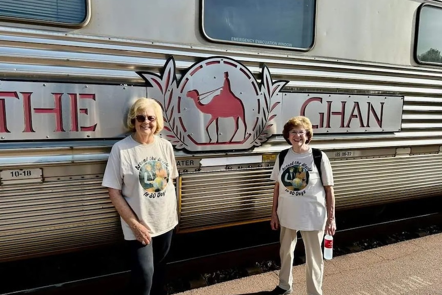 Two ladies standing in front of a silver carriage with the words the Ghan printed on the side