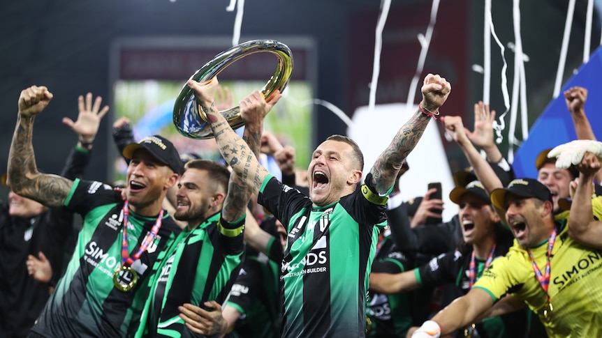 Western United players smile and shout with their arms up lifting a trophy