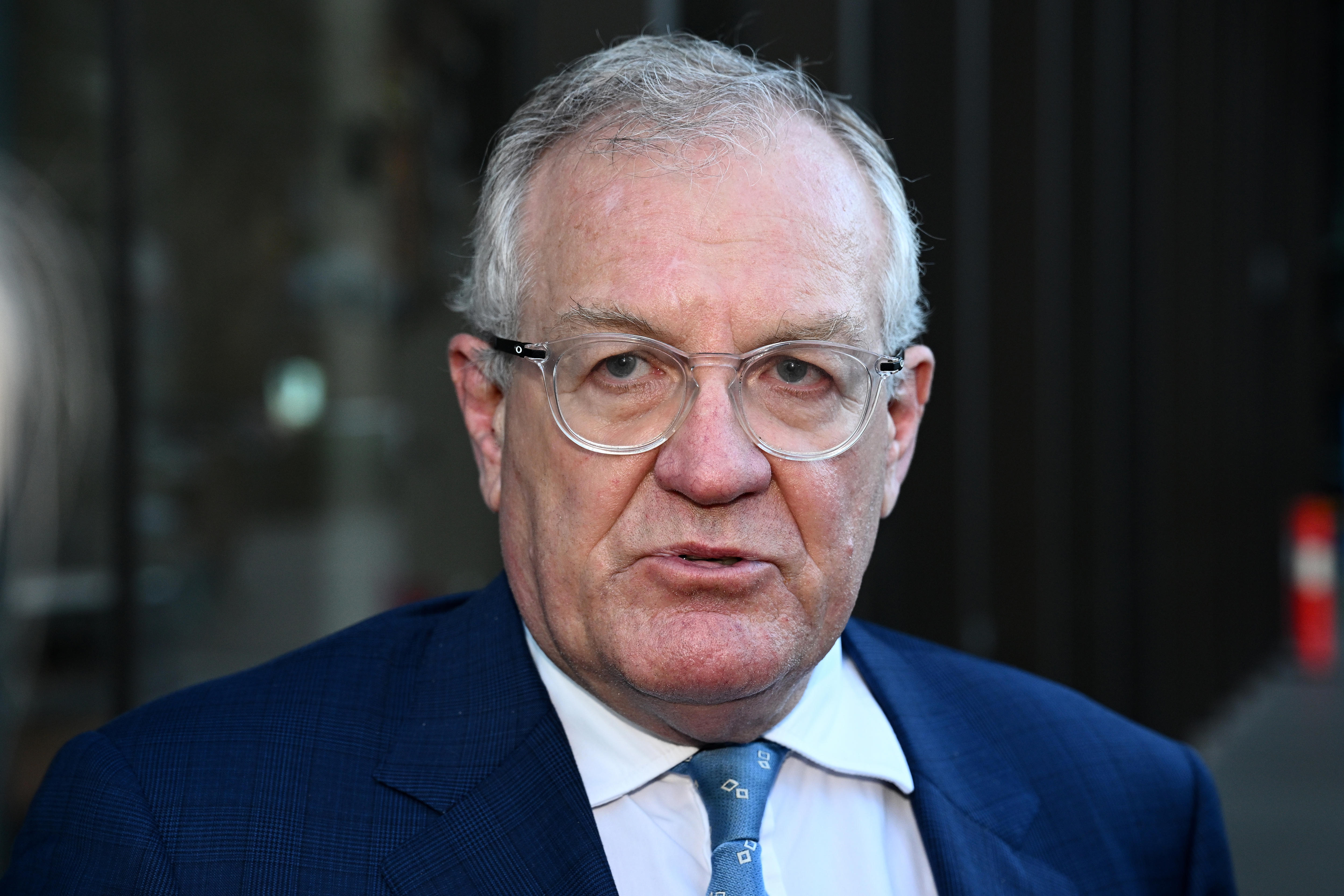 A man wearing a suit and tie and glasses