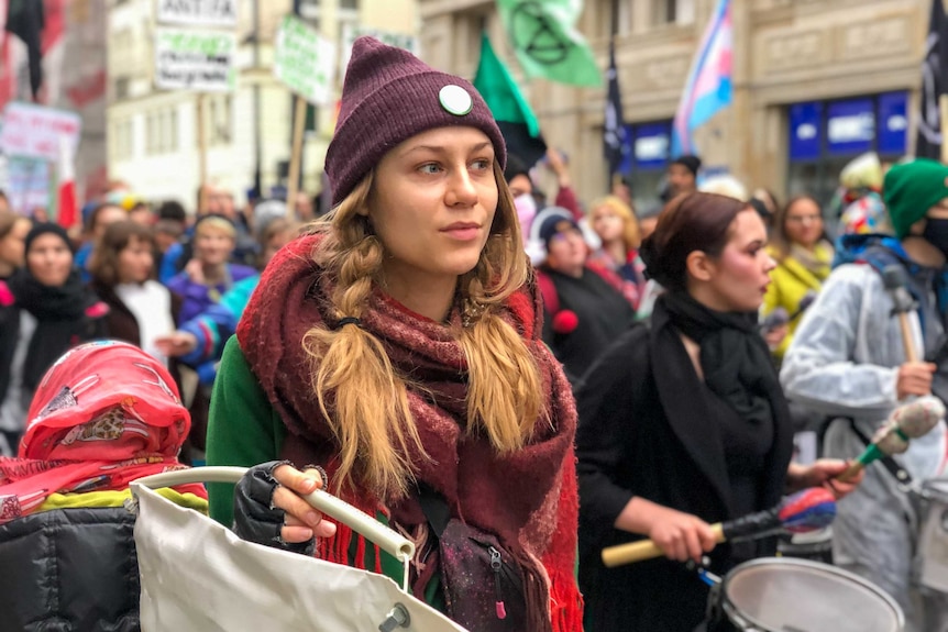 A woman in a beanie walking with protesters