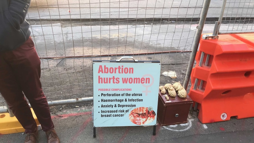 An anti-abortion sign sits beside small models of human foetuses