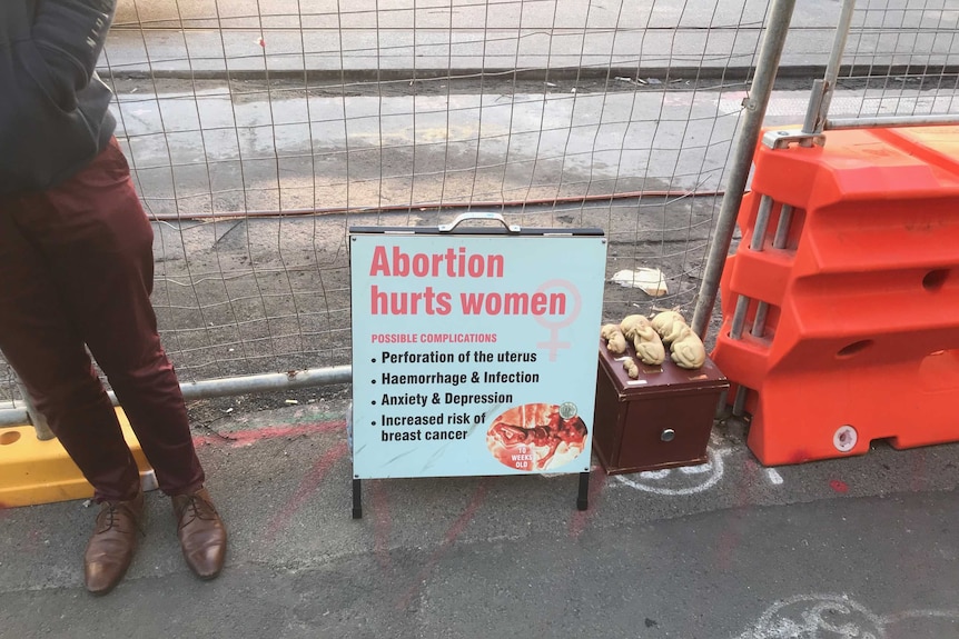An anti-abortion sign sits beside small models of human foetuses