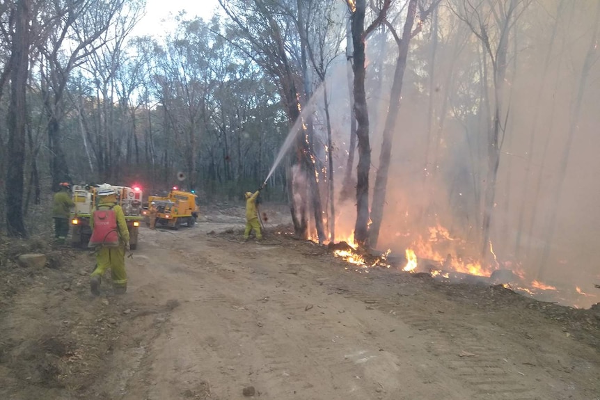 Volunteer rural firefighter Andrew Ruddock uses a hose on a fire.