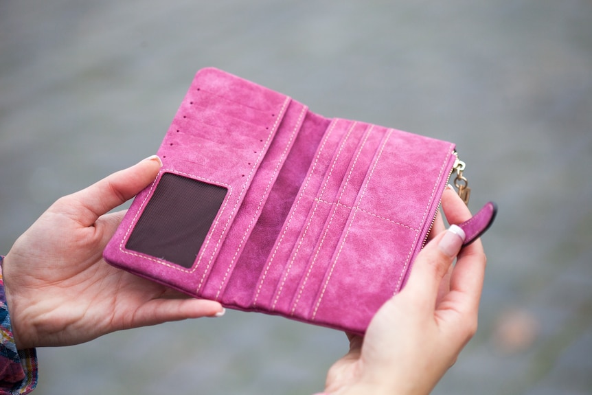 Woman holding open an empty pink wallet