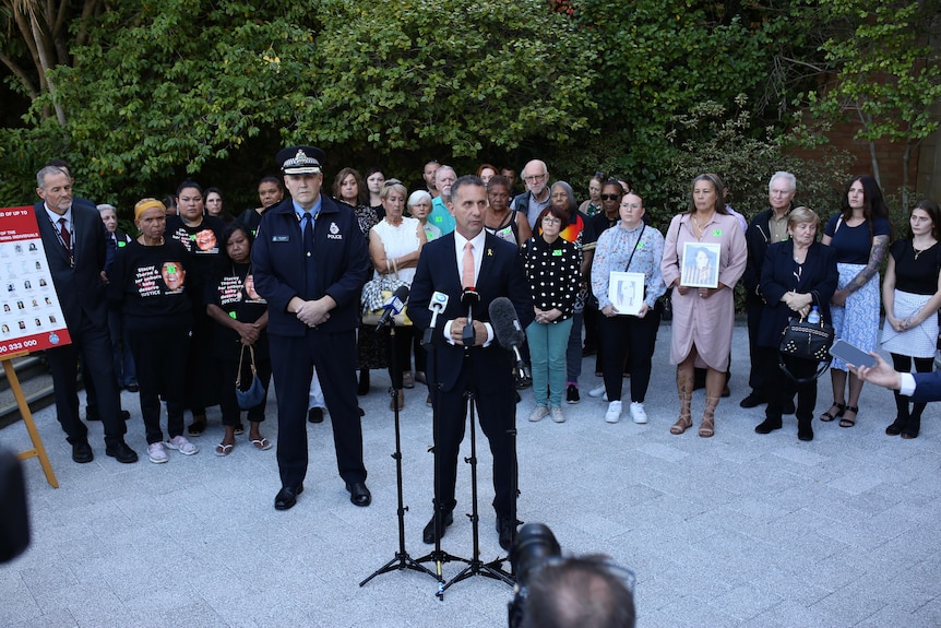 Families of victims stand behind the police minister and commissioner