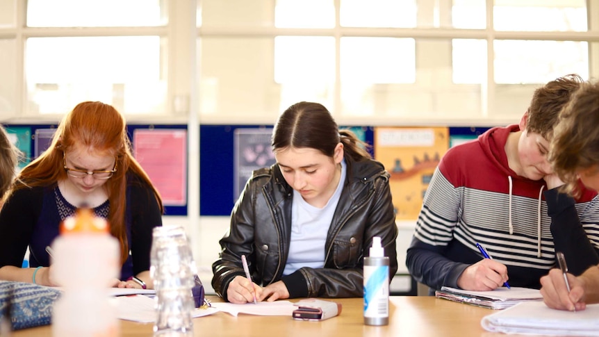 Dickson College students write on paper at a desk