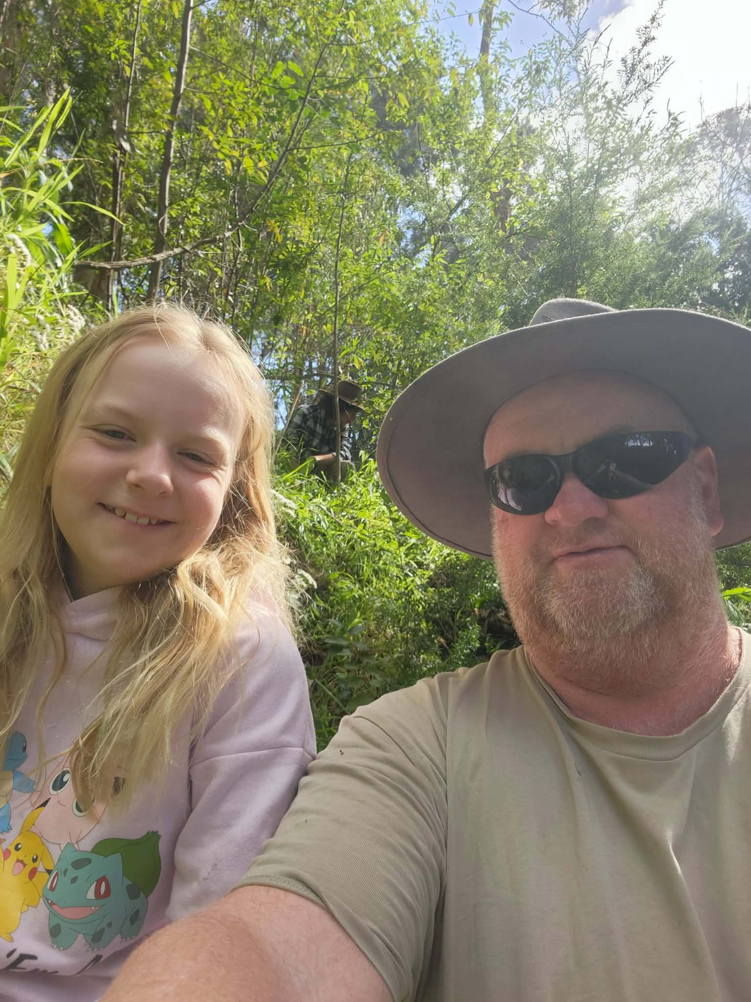 Hombre con barba clara, gafas y sombrero sonríe con su pequeña hija