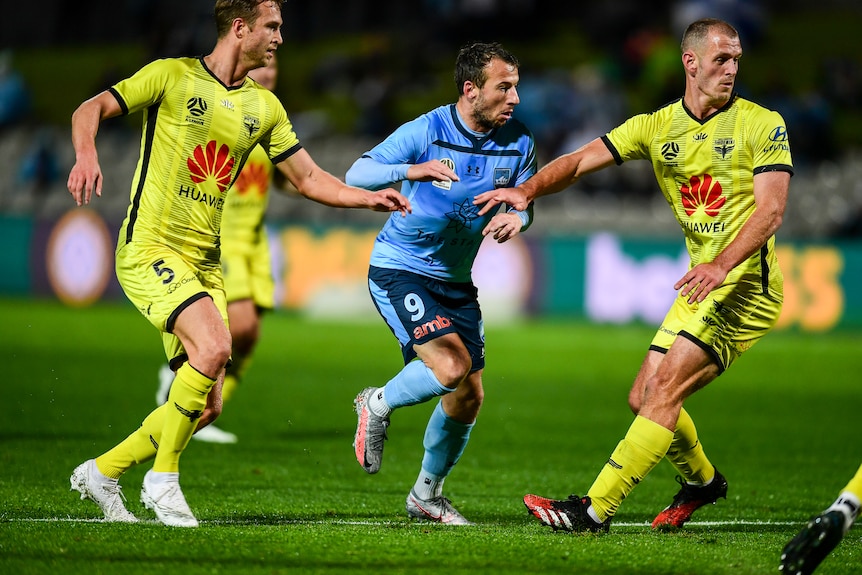 Adam le Fondre runs between two players wearing yellow football kit