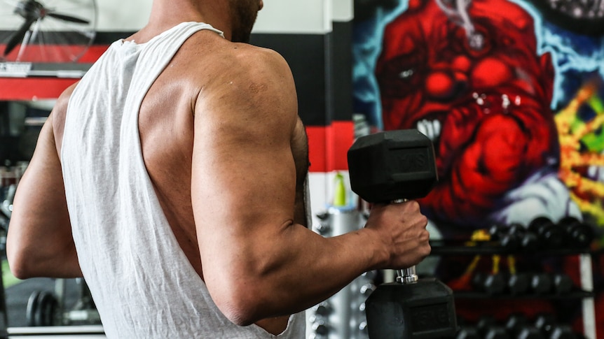 The back of a man lifting weights.