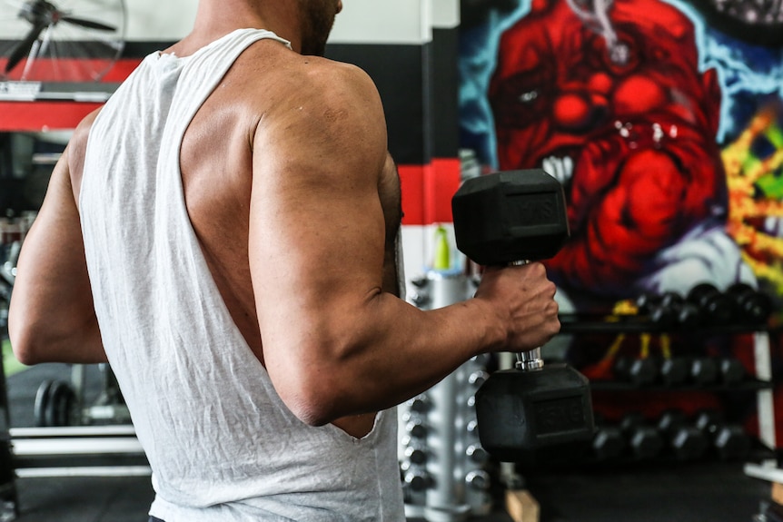 The back of a man lifting weights.