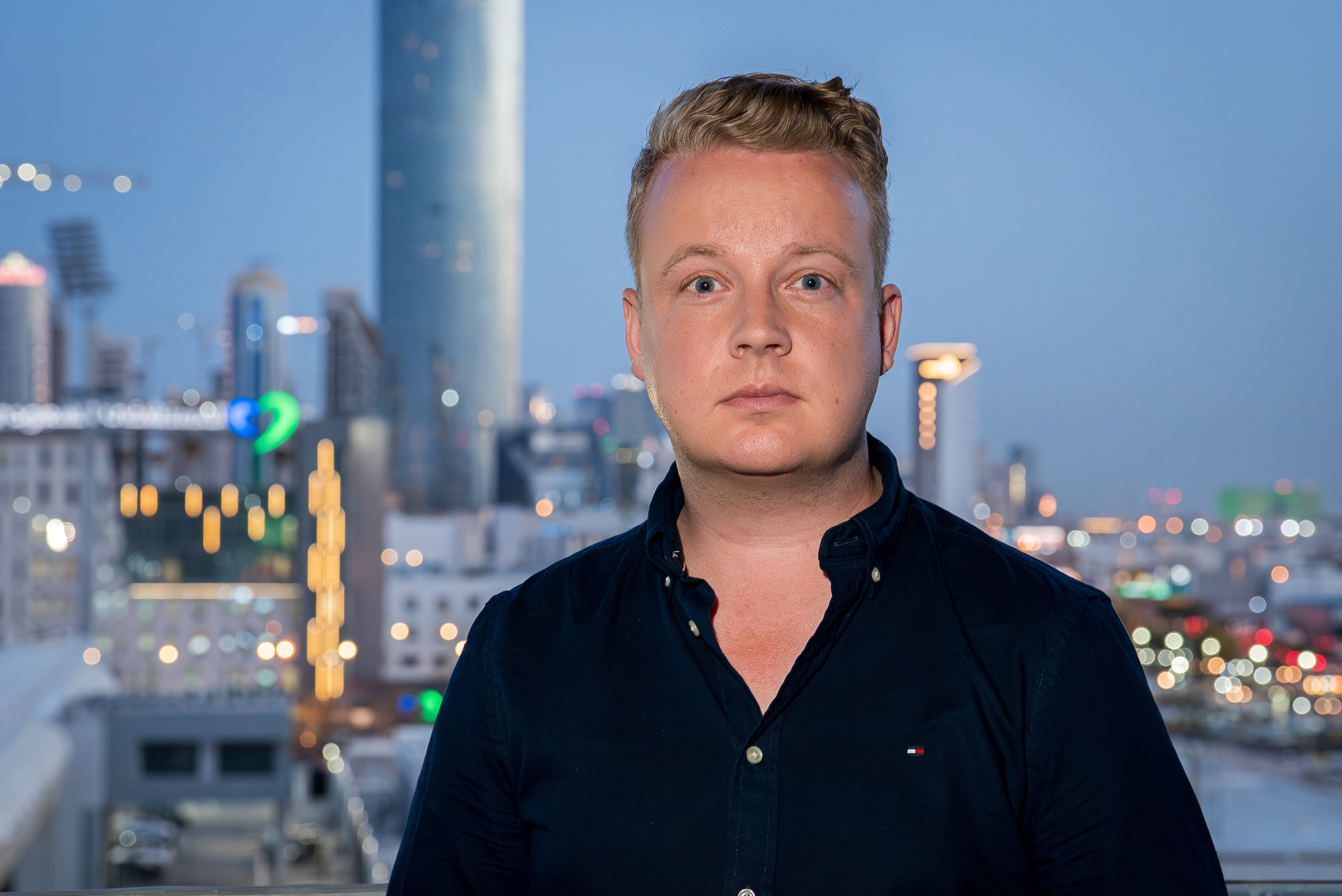 Matthew Doran standing in front of the evening skyline of Riyadh.