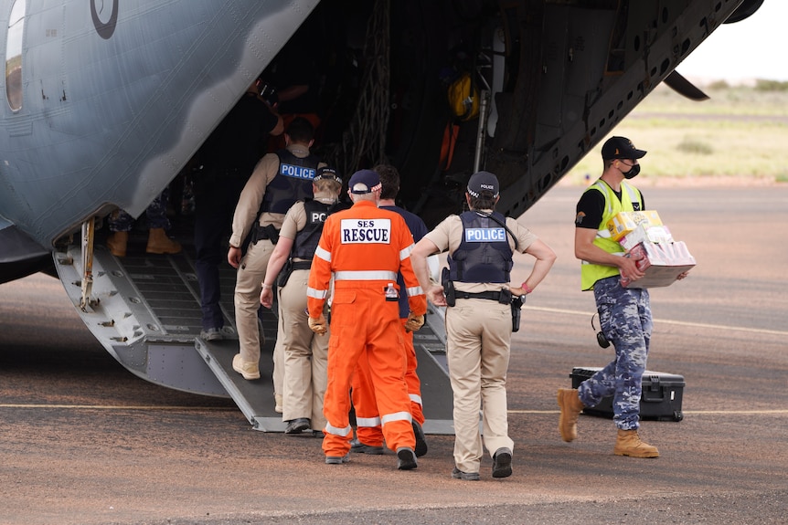 People take items from the back of a large green aeroplane