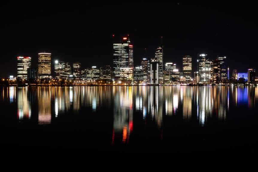 Line of brightly lit city buildings reflected in the Swan River