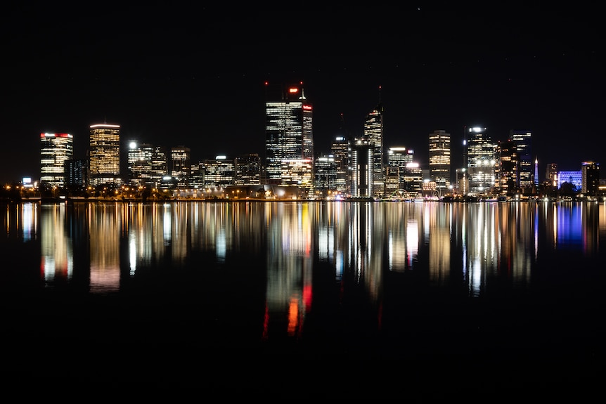 Line of brightly lit city buildings reflected in the Swan River