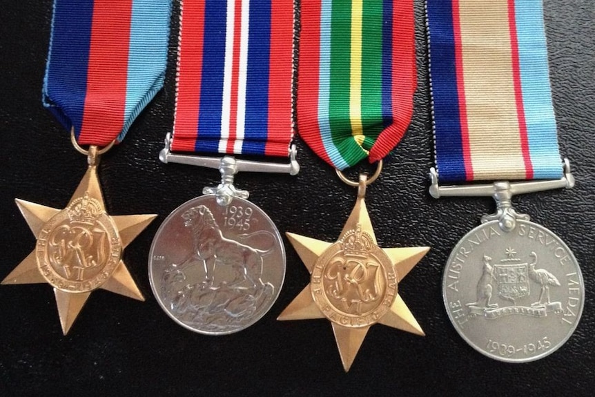 four war medals on colourful ribbons lined up and sitting on a black background