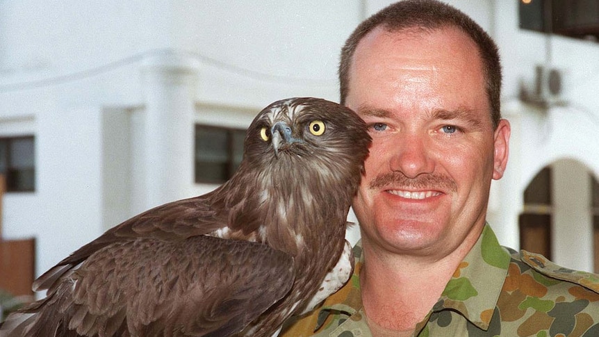 Australian Army soldier Brian Hartigan in army fatigues, with the unit mascot, an owl named Bob, in East Timor