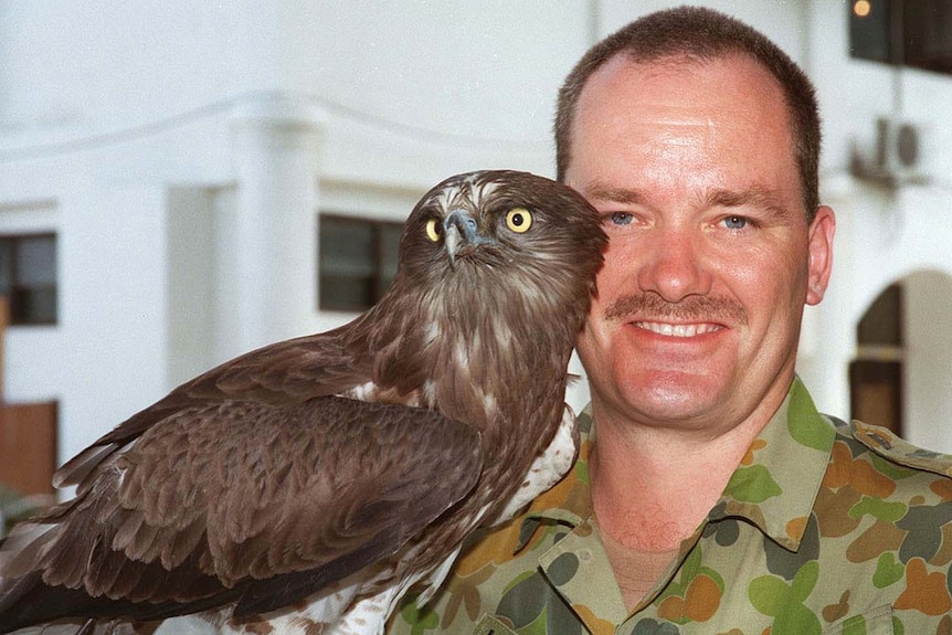 Australian Army soldier Brian Hartigan in army fatigues, with the unit mascot, an owl named Bob, in East Timor