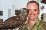 Australian Army soldier Brian Hartigan in army fatigues, with the unit mascot, an owl named Bob, in East Timor
