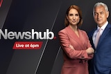 A Newshub advert with two news presenters on it. One female in a pink suit and one male in a blue suit.