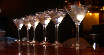 A line of cocktail glasses on a dark-coloured bar