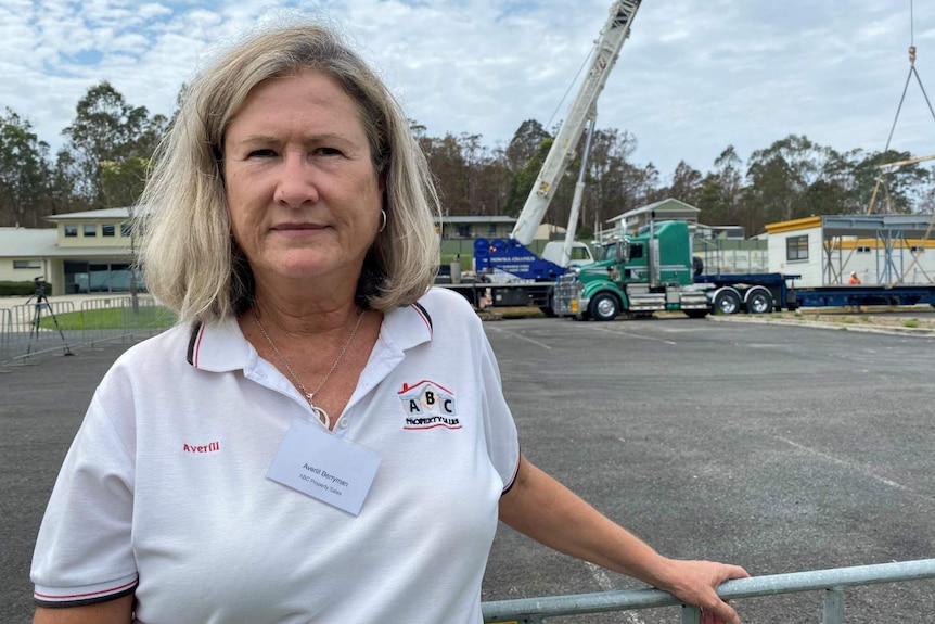 woman in white shirt and name tag standing in front of trucks