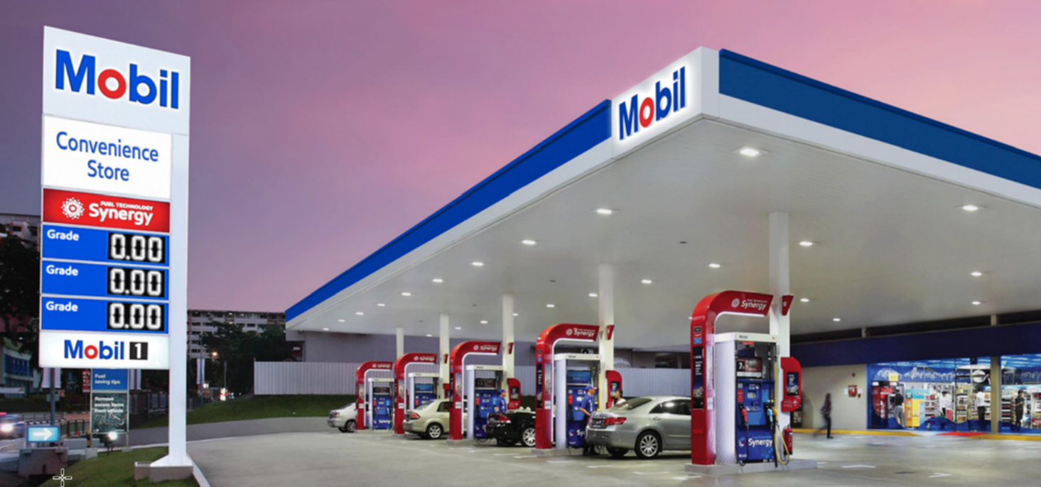 A Mobil petrol station at sunset with cars parked at bowsers