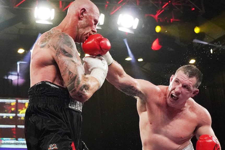 A boxer leans in to land a punch on his opponent in the ring