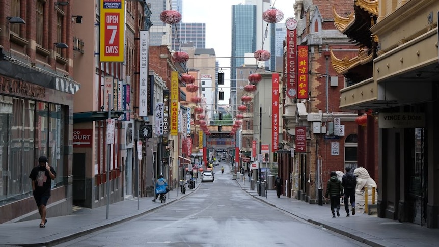 Restaurants line a street in Melbourne's Chinatown but the road  is empty except for one delivery driver and three pedestrians.