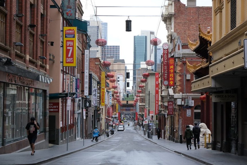 Restaurants line a street in Melbourne's Chinatown but the road  is empty except for one delivery driver and three pedestrians.