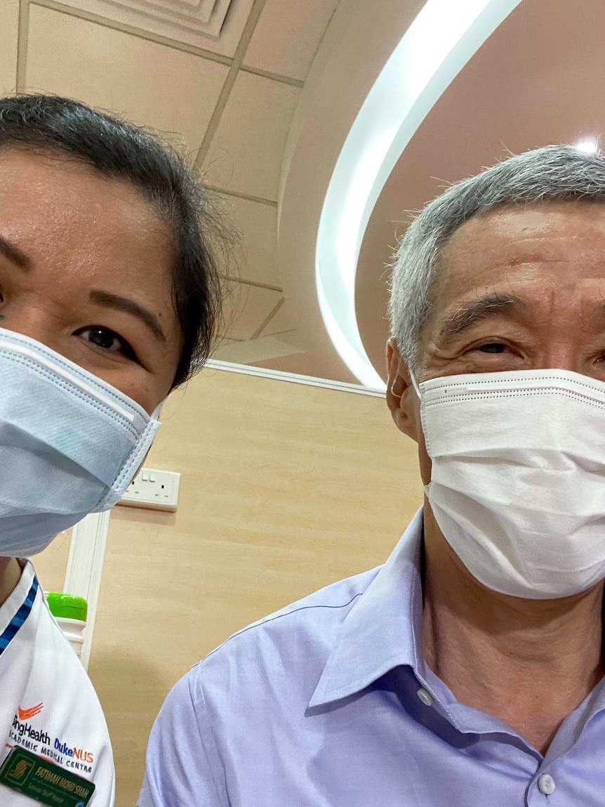 Singapore's Prime Minister Lee Hsien Loong takes a selfie with the nurse who vaccinated him against COVID