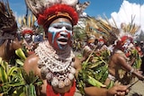 Dancers with shell necklaces and feathered headdresses and blue, white and red face paint at a Jiwaka election rally.