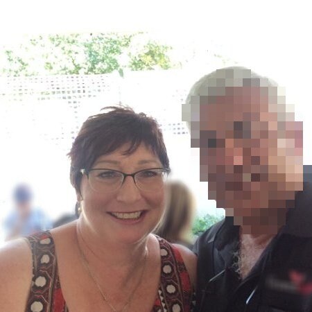 A smiling woman with short hair next to a man whose face is blurred
