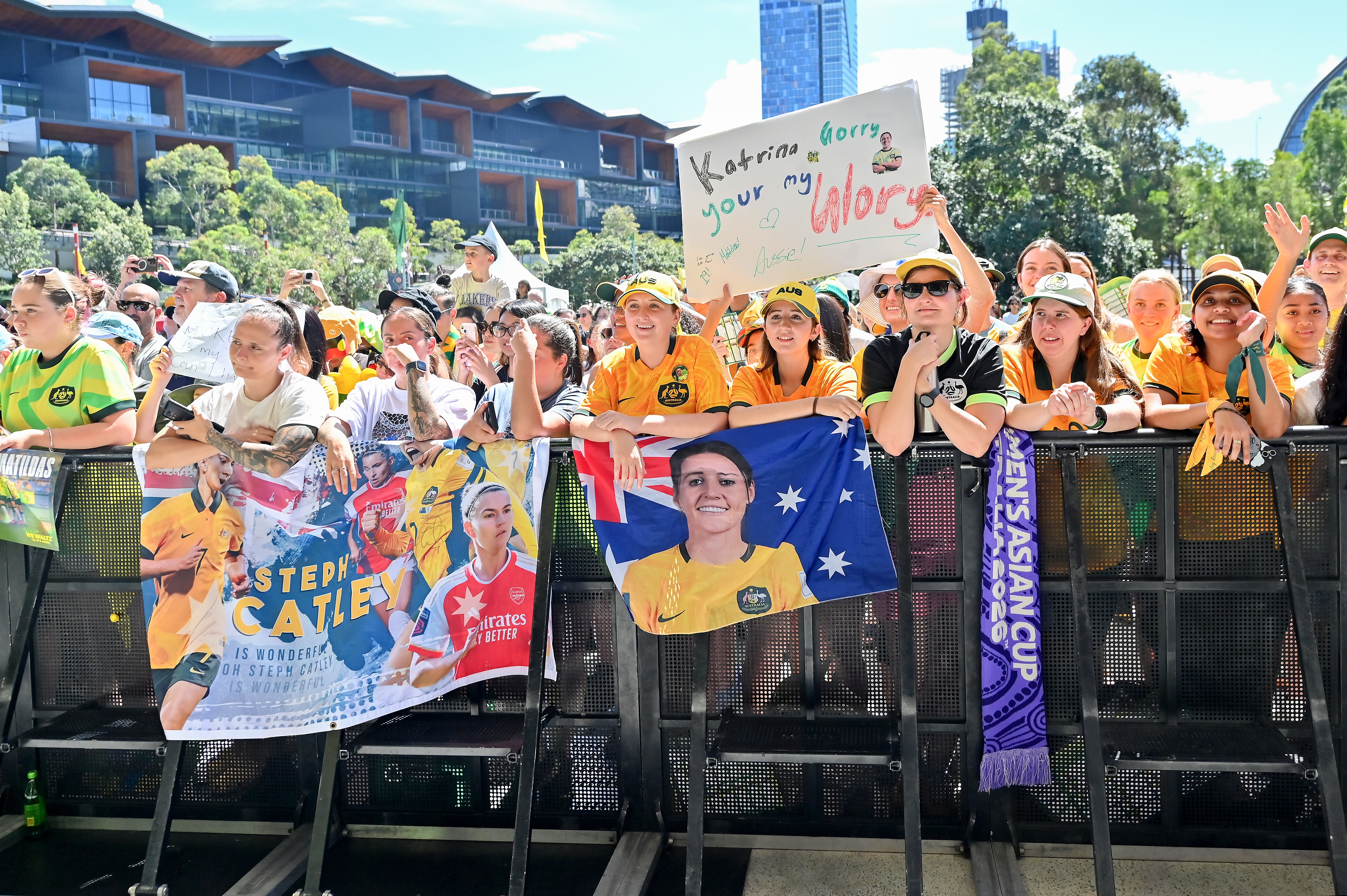 Torcedores de Matildas seguram cartazes enquanto esperam para ver os jogadores no palco