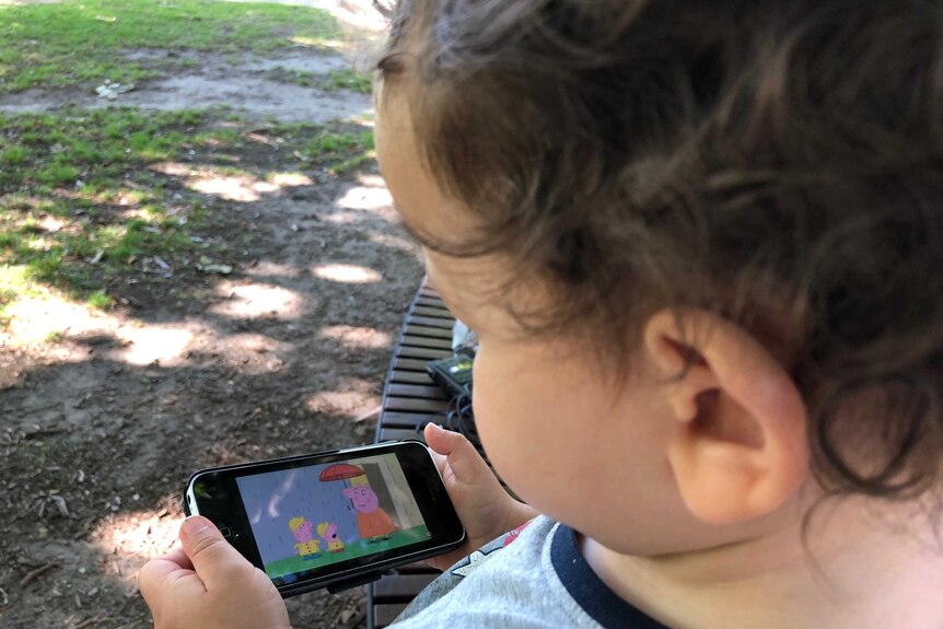 Toddler uses an app on his dad's iPhone.