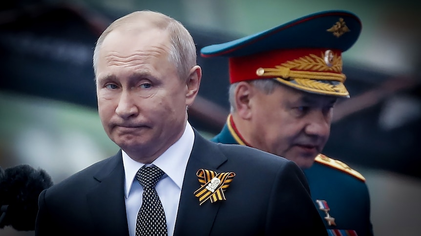 Vladimir Putin looking thoughtful while a Russian military general in dress uniform passes behind him