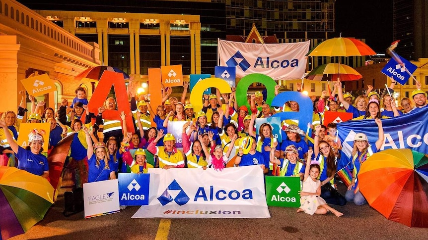 A group of people hold colourful umbrellas and posters