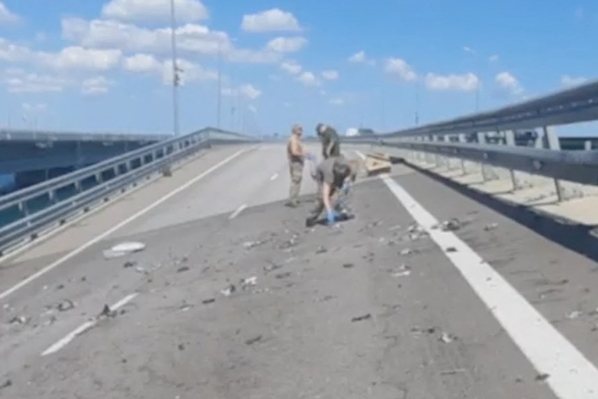 Men crouching on a very slanty bridge