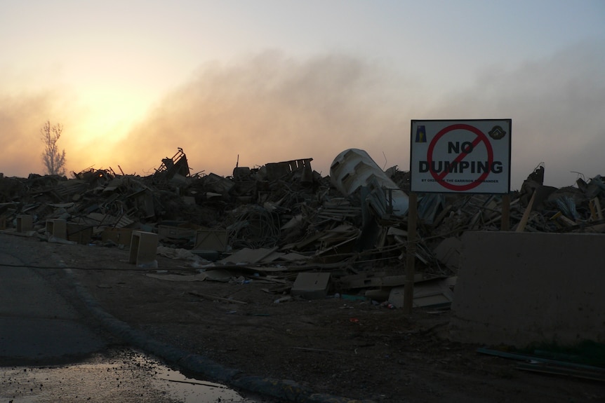 Burn pit in Iraq with a sign saying 'no dumping'.