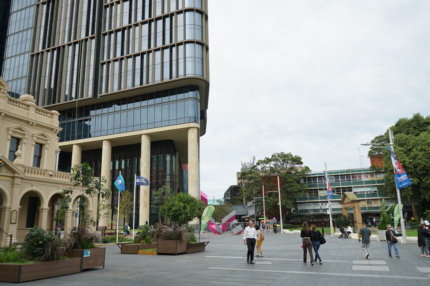 an open plaza with a tall building and people walking around