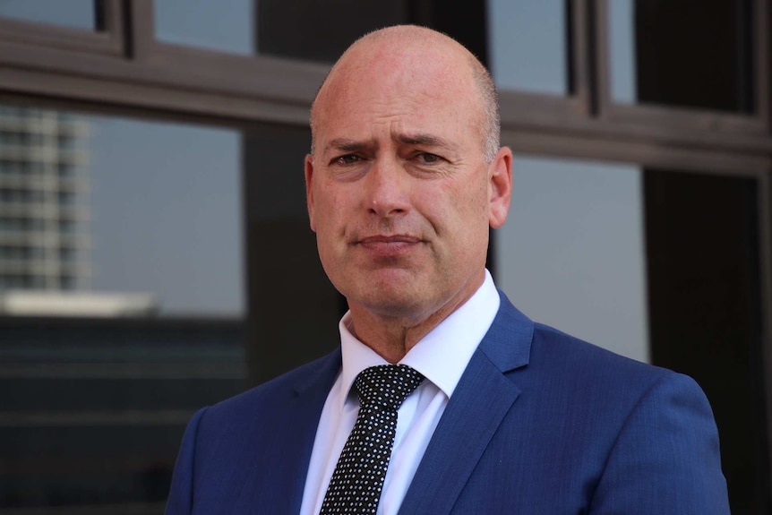 A head and shoulders shot of WA Treasurer Dean Nalder wearing a blue suit and black tie outside State Parliament.