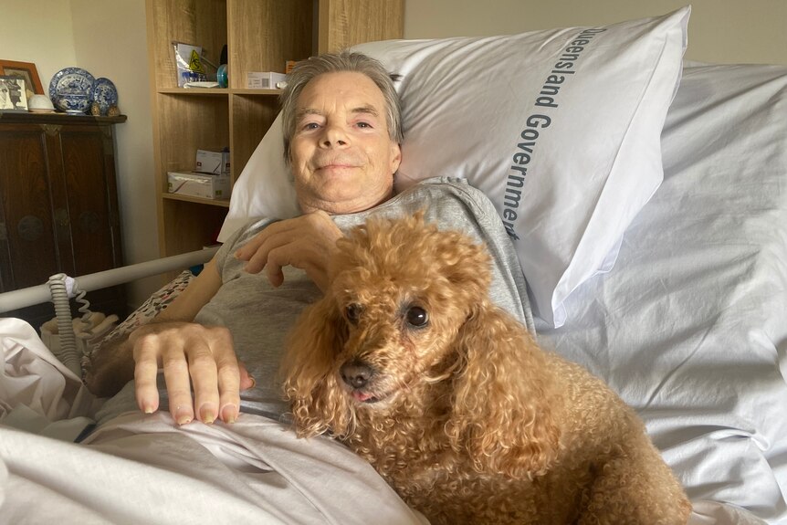 A man in a hospital bed with a poodle