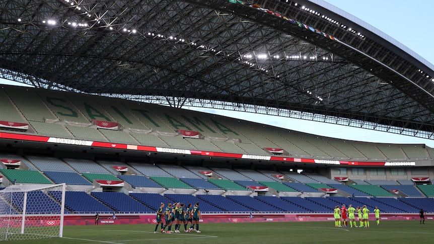 Two groups of players gather in an empty stadium