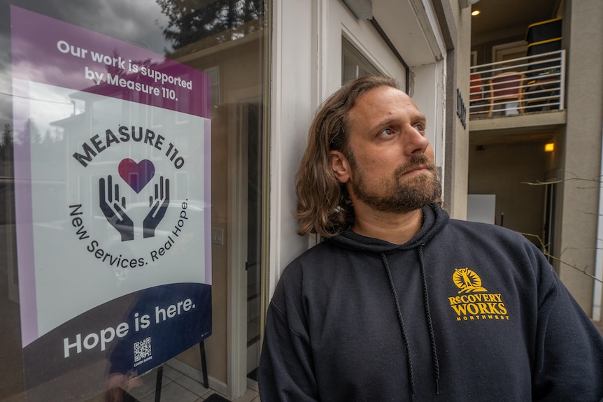 A man stands outside the window of a drug treatment clinic.
