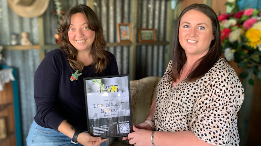 Two leaders of new Canungra arts group in a shed smiling holding plaque about the 4275 Collective 