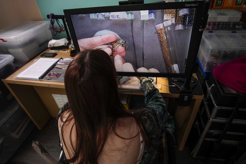 Visually impaired beader Asha Martin uses a video screen to enhance vision of her beading work.
