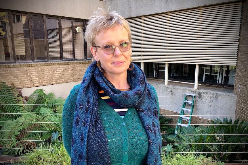 a lady with blond hair and glasses looks at the camera
