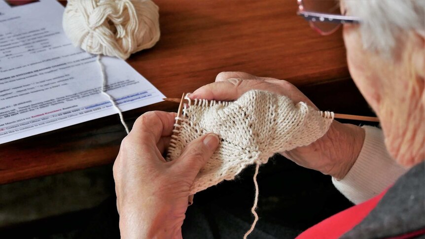 A close up of a pair of hands knitting a knocker.