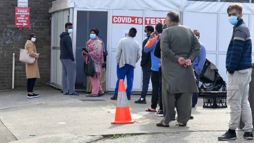 people wearing masks outside a tent set up to be a testing clinic