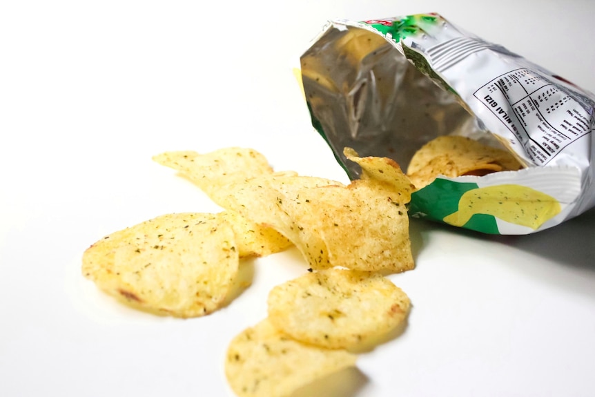 Crisps with green flecks spilling out of an open bag