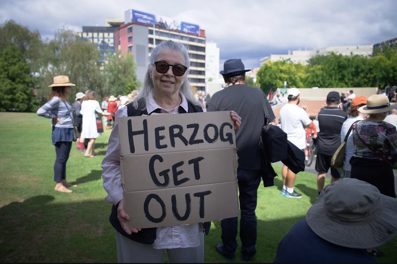 Josephine Ann-Smith se encuentra en medio de una multitud en un parque, sosteniendo un cartel que dice 